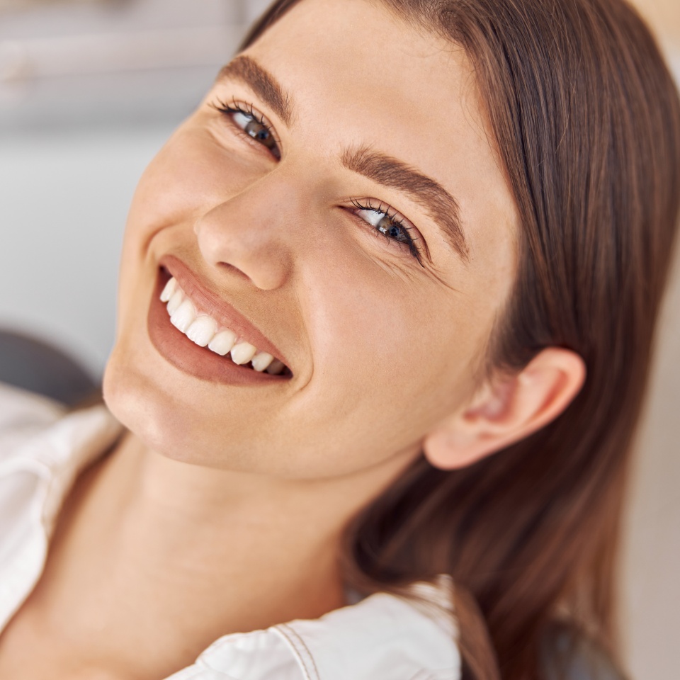 Attractive woman visiting dental clinic. Happy young woman sitting in dental chair at dentist office