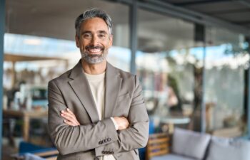 Happy middle aged business man entrepreneur looking at camera outdoors. Smiling confident mature businessman professional executive, successful lawyer wearing suit standing arms crossed, portrait.