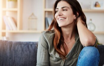 Relax, couch and woman in home for thinking, smile and living room for alone and break on weekend. Happy, calm and ideas in apartment for female person, lounge and comfort on sofa in Los Angeles