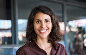 Closeup headshot face portrait of beautiful successful hispanic young business woman looking confident at camera. Smiling latin or eastern middle age female ceo leader businesswoman standing in office