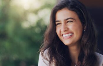 Happy, woman and face in nature for thinking, positive mindset and carefree with mockup space. Female person, smile and inspiration in natural environment for wellness, peace and relaxing in Portugal