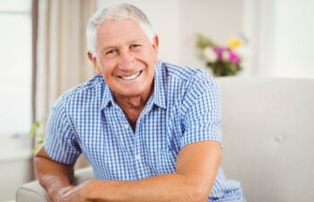 Senior man looking at camera and smiling in living room